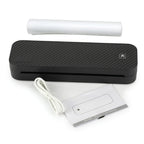 Imprimante thermique portable A4 noire sur fond blanc, présentée avec ses accessoires fournis : un rouleau de papier thermique, un câble USB blanc et un manuel d'utilisation.